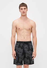Shorts de bain noirs avec un motif ondulé gris foncé, taille élastique avec cordon de serrage et poches latérales pour plus de fonctionnalité.