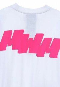 Camiseta blanca con un gran texto gráfico en rosa intenso en la parte de atrás. El diseño tiene bordes afilados y una apariencia estilizada e irregular.