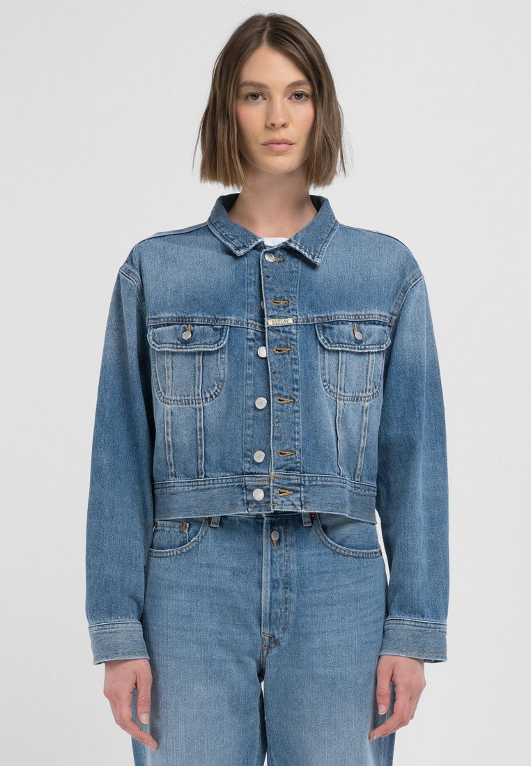 Kort denimjacka i ljusblått med klassisk krage, fyra framfickor och silverfärgad knappstängning, med en vitskatta textur.