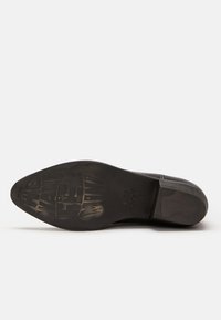Czarne skórzane buty z eleganckim, spiczastym noskiem. Podeszwa ma teksturowany wzór i logo, co wskazuje na trwałą konstrukcję.