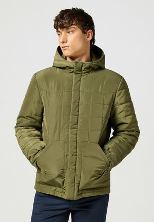 Chaqueta acolchada de color verde oliva con textura acolchada, bolsillos frontales, capucha y cierre de cremallera. Presenta una silueta ajustada.