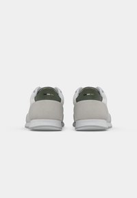 Pair of gray and white sneakers with dark green heel tabs and small black, white, and beige details on a white background.