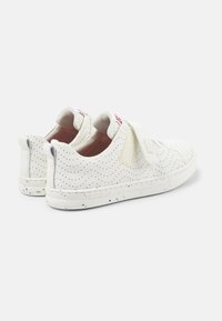Sneakers bianchi con tomaia perforata, fascia in velcro e suola in gomma testurizzata con accenti di vernice spruzzata. Design slip-on con collare imbottito.