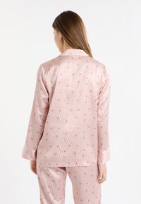 Conjunto de pijama a rayas rosas con un patrón floral estilo cóctel. Tejido suave con mangas largas y ajuste relajado. Detalles florales destacables por todo el conjunto.
