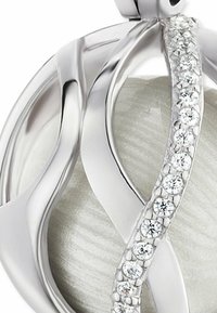 Silverhänge med sammanflätad design, med en texturerad, ljusgrå mitt och dekorerat med små klara stenar på ena sidan.