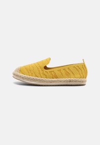 Geltonos espadrilės su tekstūruotu megztu viršumi, apvaliu dzūgumu ir džute apvartuotu padu. Lengvai uždedamas dizainas su užkulnio kilpute patogiam dėvėjimui.