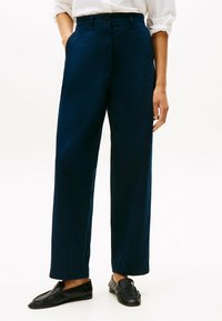 Pantaloni a gamba larga blu navy realizzati in tessuto morbido, con parte anteriore piatta, tasche laterali e chiusura a un bottone.