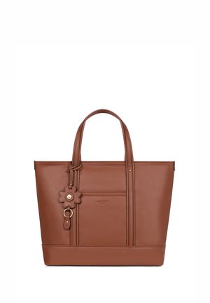 Brązowa torba typu tote ze skóry z podwójnymi górnymi uchwytami, przednią kieszenią oraz zawieszką w kształcie kwiatu przyłączoną do jednego uchwytu.