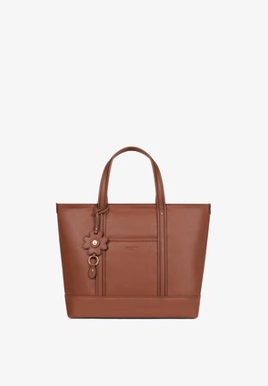 Brązowa torba typu tote ze skóry z podwójnymi górnymi uchwytami, przednią kieszenią oraz zawieszką w kształcie kwiatu przyłączoną do jednego uchwytu.