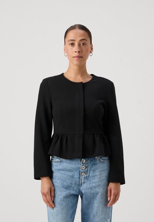 Zwarte peplumjas met lange mouwen, ronde halslijn en een sluiting met knopen aan de voorkant, gecombineerd met lichtblauwe denim jeans. Eenvoudig, strak ontwerp.