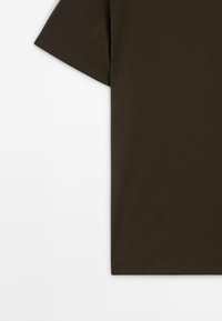 T-shirt a maniche corte marrone scuro con una texture liscia e scollatura rotonda, caratterizzato da un orlo pulito e un design minimalista.