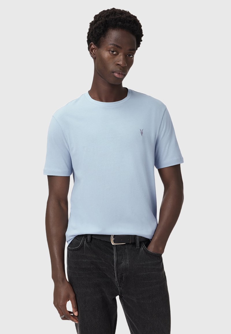 Lyseblå kortærmet t-shirt i blød bomuld, med rund hals og lille logo broderet på venstre bryst, parret med mørke jeans.