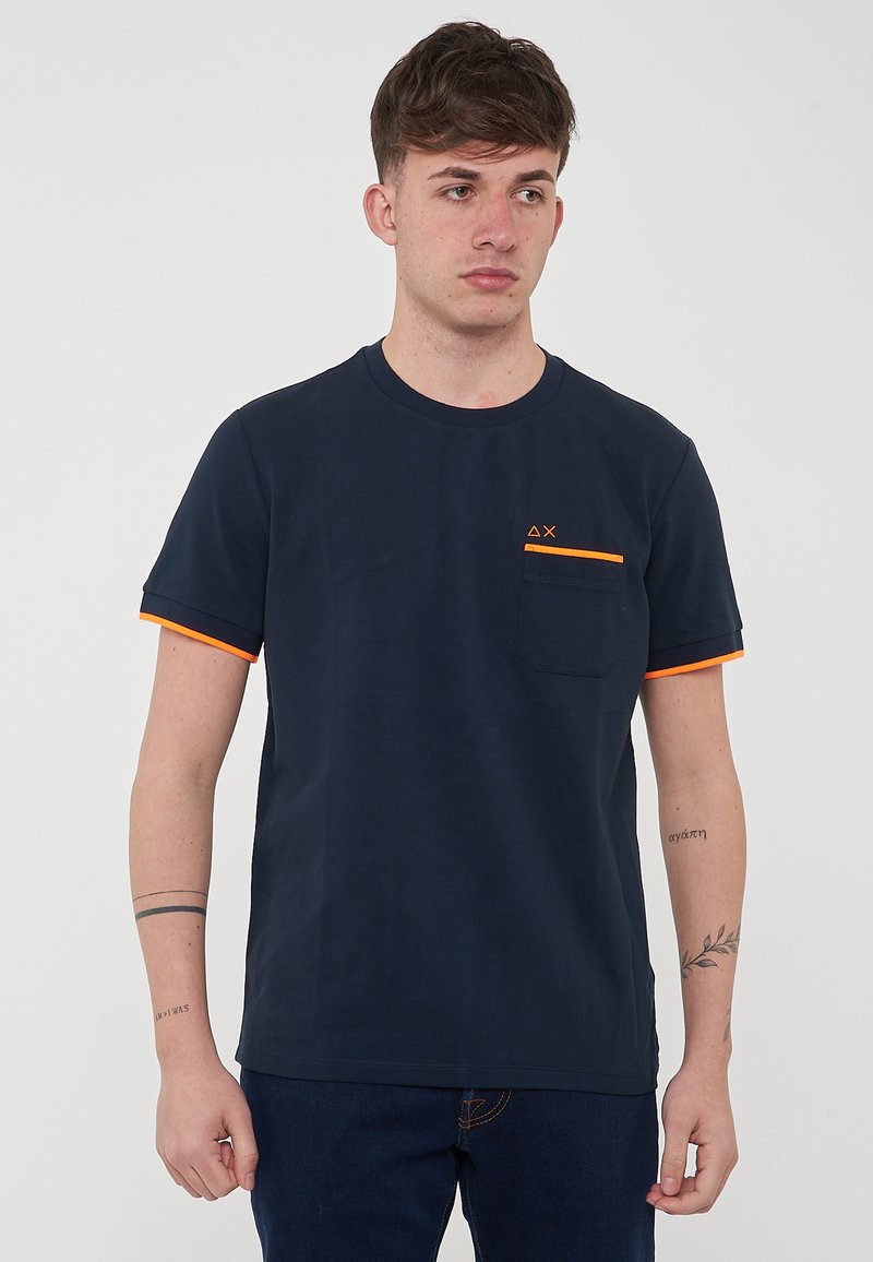 T-shirt in cotone blu navy con dettagli arancioni, scollo rotondo, maniche corte e taschino sul lato sinistro con logo.