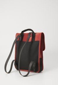 Red and black backpack with smooth leather and fabric materials. Adjustable black straps with buckles. Rectangular shape with a top handle.