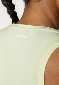 Light green athletic tank top with a round neckline. Features white "STRONGER" branding on the back. Smooth texture and fitted design.