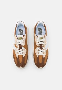 Braune und beige Sneakers mit einem Obermaterial aus Mesh und Wildleder, weißen Schnürsenkeln und einer strukturierten Zwischensohle. Logo auf der Zunge sichtbar.