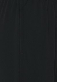 Black fabric trousers featuring a smooth texture, elastic waistband, and a side seam with stitched detailing. Simple design.