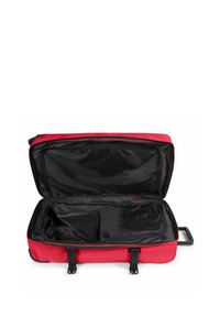 Red suitcase with a black interior, zip closure, and two exterior straps. Contains an inner pocket for organization, rectangular shape.