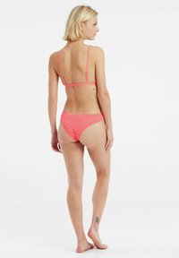 Set di bikini rosa con spalline sottili e texture a coste. La parte posteriore presenta una chiusura a scatto; la parte inferiore ha un taglio a vita bassa.