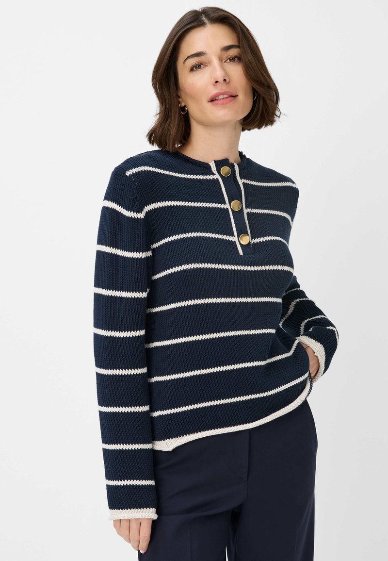 Navyblauwe gebreide trui met witte horizontale strepen, met een henley-halslijn en drie gouden knopen. Geribbelde manchetten en zoom.