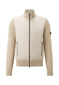 Beige zip-up jacket with stand collar, ribbed cuffs and hem, zip pockets on front, and black circular logo on left sleeve.