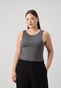 Gray sleeveless top made from smooth, stretchy material with a rounded neckline, paired with black elastic-waist trousers.