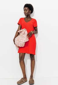 Robe rouge à manches courtes avec un col en V, assortie à un sac à carreaux rose et des chaussures à enfiler imprimé léopard. Tissu lisse et design décontracté.