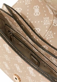 Sac à main beige avec un motif floral, extérieur lisse, fermeture à pression sur le dessus, et plusieurs compartiments intérieurs, dont une poche zippée.