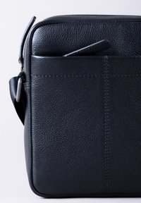 Black leather messenger bag with a textured surface, featuring a front pocket and an adjustable shoulder strap. Stitched accents visible.