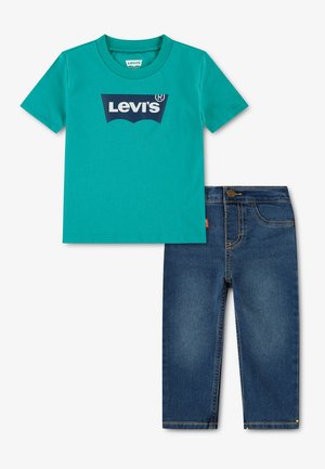 T-shirt turquoise à manches courtes avec logo Levi's bleu foncé associé à un jean en denim bleu foncé avec des surpiqûres jaunes.