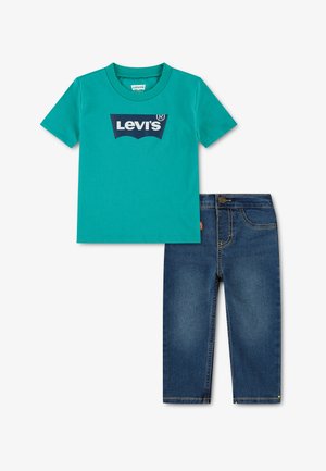 Turquoise T-shirt met korte mouwen en donkerblauw Levi's-logo, gecombineerd met donkerblauwe spijkerbroek met gele stiksels.