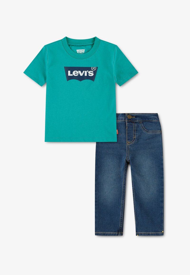 T-shirt turquoise à manches courtes avec logo Levi's bleu foncé associé à un jean en denim bleu foncé avec des surpiqûres jaunes.