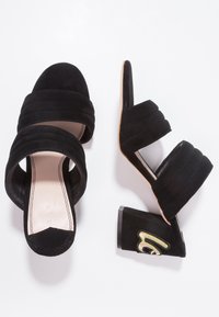 Černé semišové sandály na podpatku se třemi texturovanými páskami, zaoblenou špičkou a zdobeným blokovým podpatkem s vyšívaným akcentem.