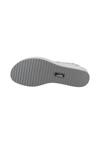 Suela de zapato de goma gris con una superficie texturizada y estriada, etiqueta de marca incrustada, forma curva y acabado suave.
