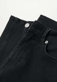 Jean en denim noir plié, montrant la braguette zippée, le bouton argenté, la boucle de ceinture et les détails de la poche avant sur fond blanc.