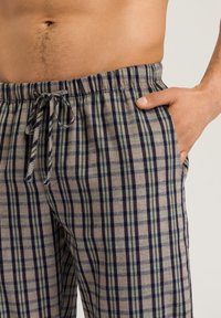 Gelaagde loungebroeken gemaakt van zacht materiaal, met een elastische tailleband, voorzakken en een kleurenpalet van grijs, marineblauw en groen.