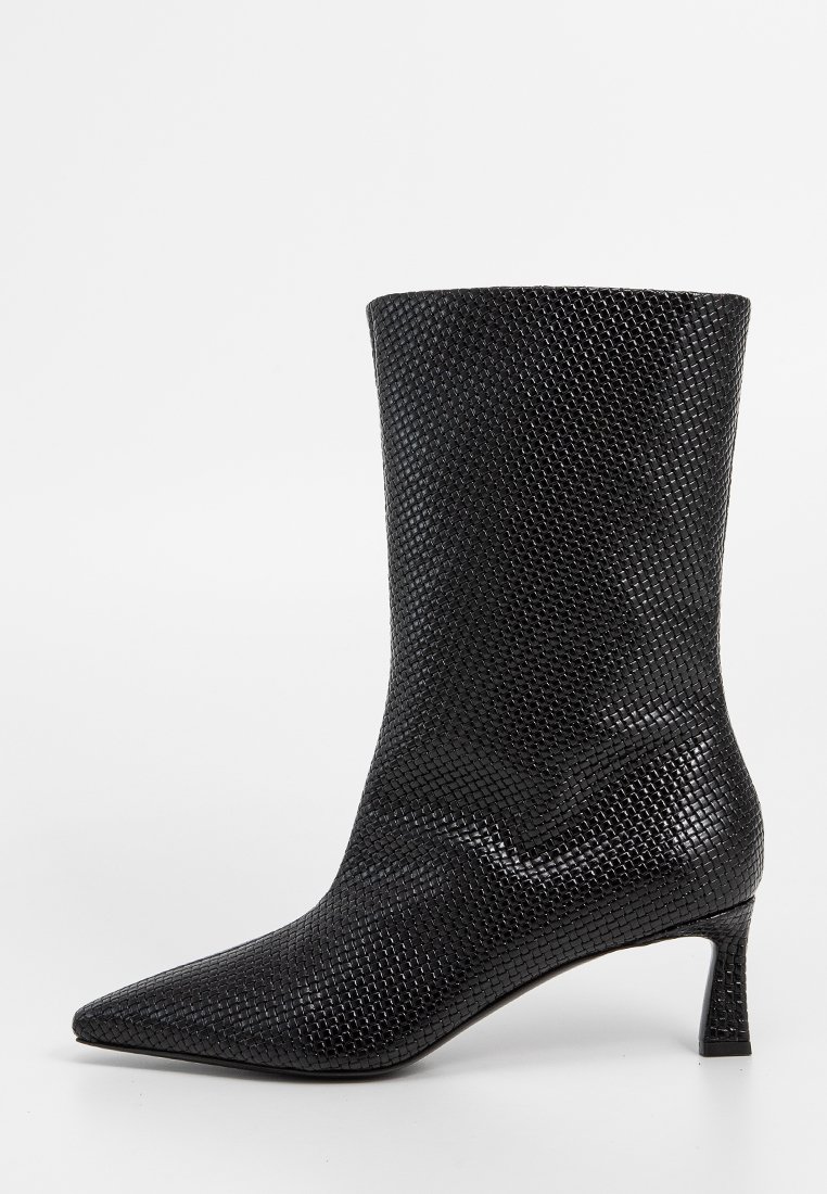 Schwarze Knöchelstiefel mit spitzem Fuß, aus strukturiertem Material mit einem Netzmuster. Sie haben einen moderaten Absatz und eine glatte Oberfläche.