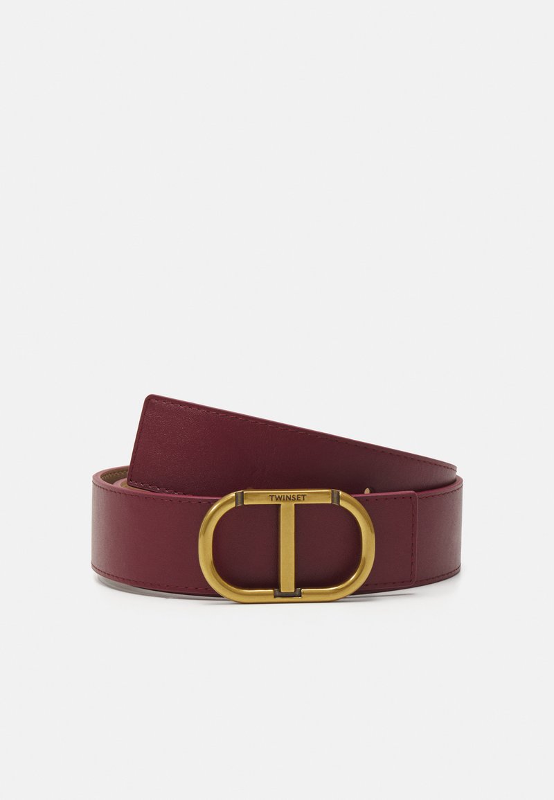 Cintura in pelle bordeaux con un grande cinturino in metallo dorato con logo centrale. Texture liscia, design ampio con bordi arrotondati.