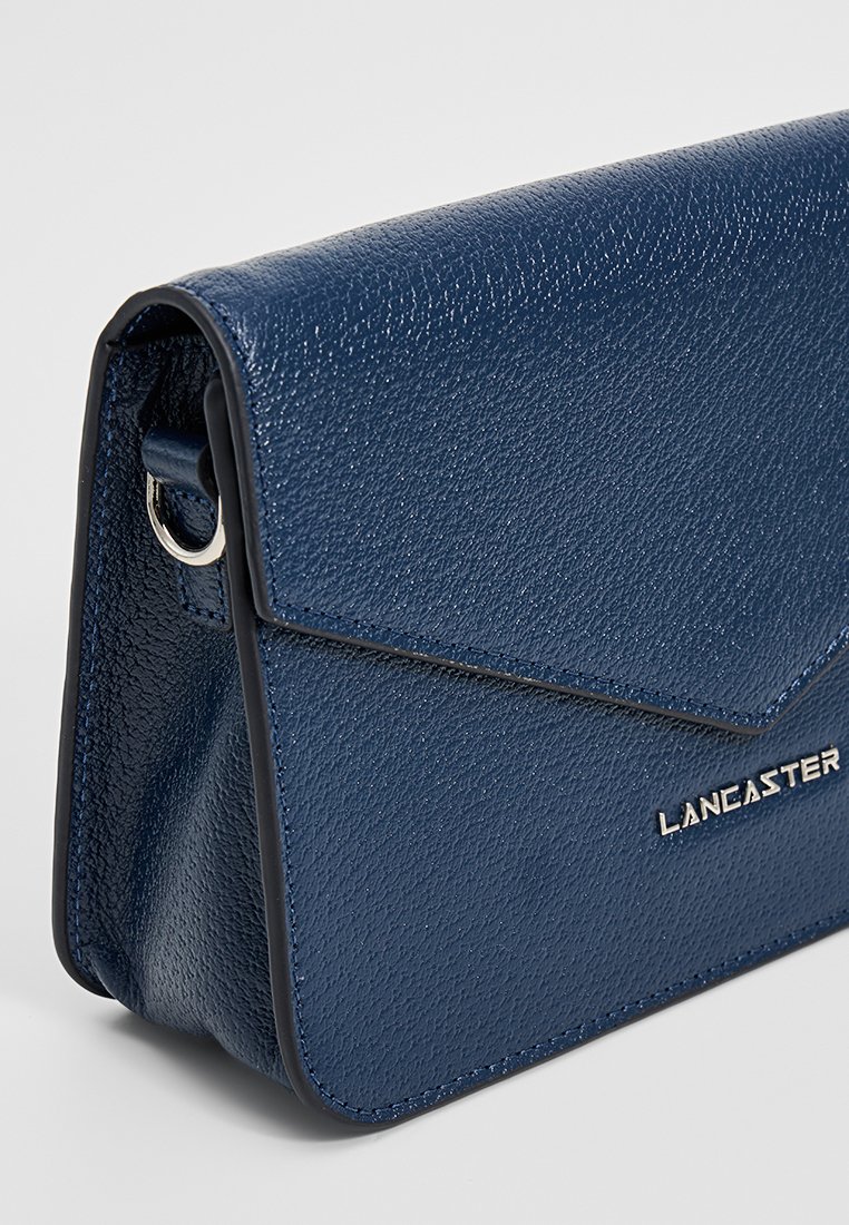 Dunkelblaue Lederhandtasche mit strukturiertem Finish, Klappenverschluss und silberfarbener Hardware. Mit Markenlogo auf der Vorderseite.