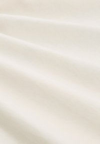 Jasno-beżowa tkanina o gładkiej fakturze, z subtelnymi zmarszczkami i fałdami, które tworzą delikatne cienie. Idealna do układania lub szycia.