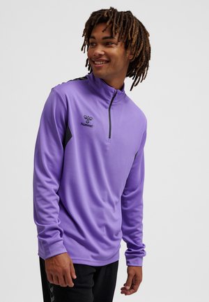 Lilla atletisk pullover med en kvart lynlås, der har sorte accenter og Hummel-logoet. Glat overflade, lange ærmer og en afslappet pasform.