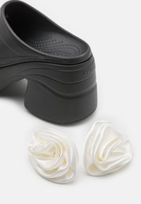 Black plastic clog with a textured upper and thick heel, paired with two white satin flower embellishments.