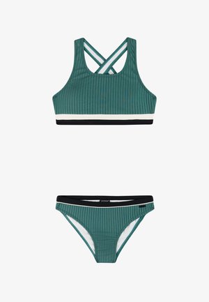 Groene geribbelde tweedelige badpak met gekruiste bandjes aan de achterkant van het topje en zwart-witte biezen op beide delen.