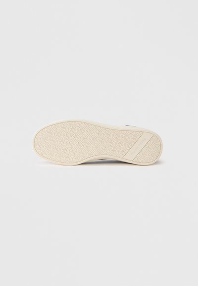 Σόλα παπουτσιού από ελαφρώς λευκό καουτσούκ, με ανάγλυφο σχέδιο και λογότυπο. Ο σχεδιασμός είναι επίπεδος και λείος με στρογγυλεμένες άκρες.