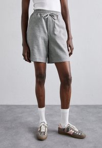 Pantaloni corti grigi in tessuto intrecciato con vita elastica e cordoncino, caratterizzati da una vestibilità comoda. Abbinati a calze bianche e sneakers a fantasia.