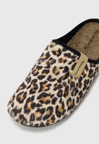 Leopárd mintás papucs, puha műszőrme anyagból, fekete díszítéssel. Természetes parafa talpbetéttel és egy kis logó címkével az oldalon.