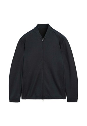 Veste noire zippée avec col montant, en tissu lisse, présentant des lignes épurées et un design minimaliste sans ornements.