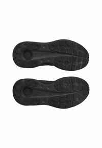 Semelles de chaussures de sport noires en caoutchouc texturé pour une adhérence, présentant des motifs circulaires et linéaires, ainsi qu'un logo en relief le long de la semelle intermédiaire.