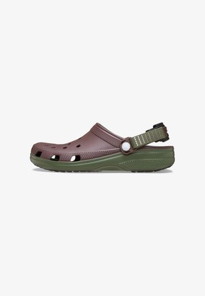 Brown and green clogs made of synthetic material with ventilation holes, textured strap, and a contrasting heel strap for secure fit.