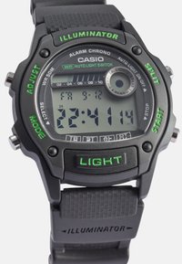 Relógio digital de pulso com caixa e pulseira de plástico preto, apresentando um mostrador com detalhes em verde, botões e uma pulseira texturizada. Exibe a hora e alarmes.